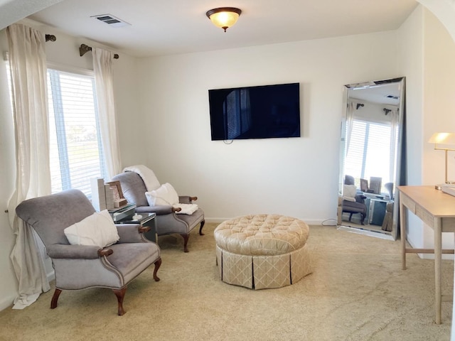 living area featuring arched walkways, visible vents, baseboards, and carpet