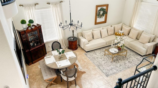 living area with tile patterned flooring, stairs, and an inviting chandelier