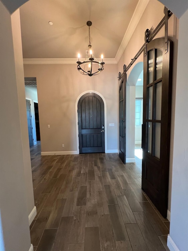 foyer entrance featuring wood finish floors, a barn door, arched walkways, and ornamental molding