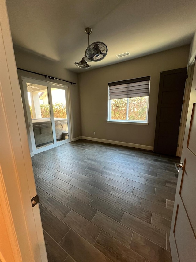 unfurnished room featuring wood finish floors, visible vents, and baseboards