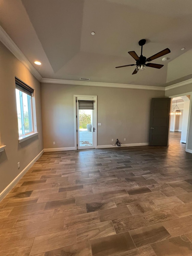 empty room featuring baseboards, crown molding, a tray ceiling, and wood finished floors