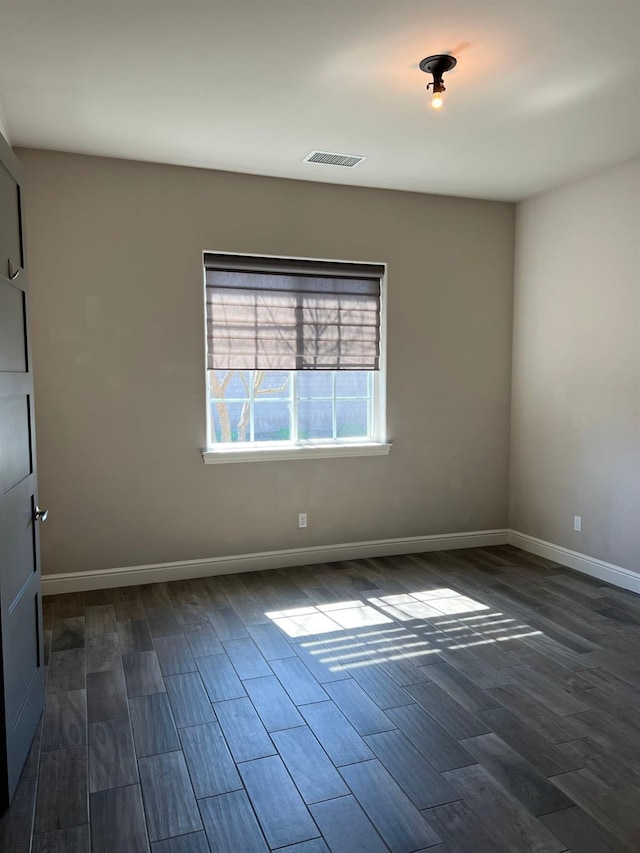 unfurnished room with visible vents, baseboards, and dark wood-style flooring