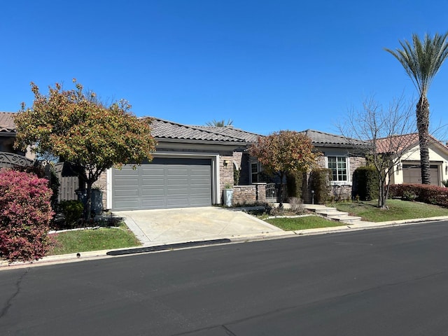 view of front of property featuring a garage, stone siding, driveway, and a tile roof