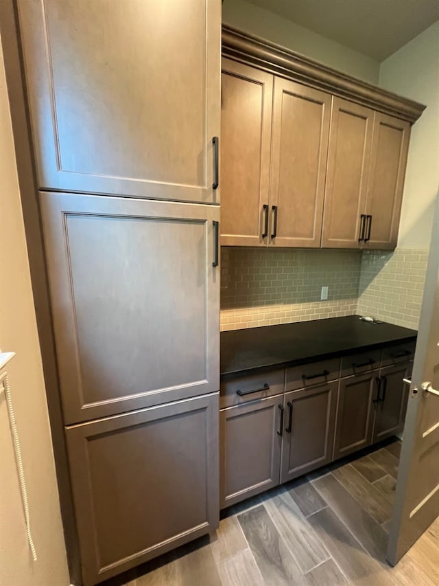 kitchen with wood finish floors, backsplash, and dark countertops