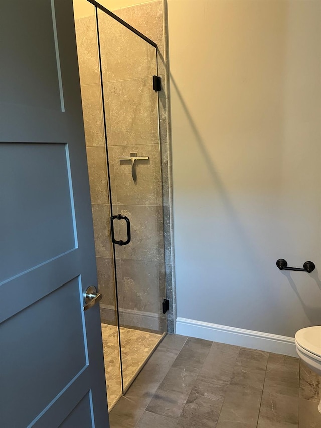 full bathroom with toilet, baseboards, and a stall shower