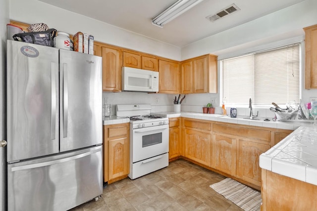 kitchen featuring tile countertops, visible vents, white appliances, and a sink