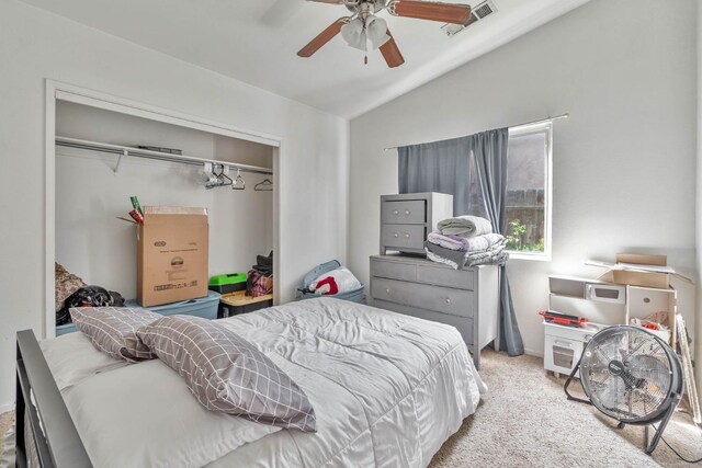 carpeted bedroom with visible vents, lofted ceiling, a closet, and ceiling fan