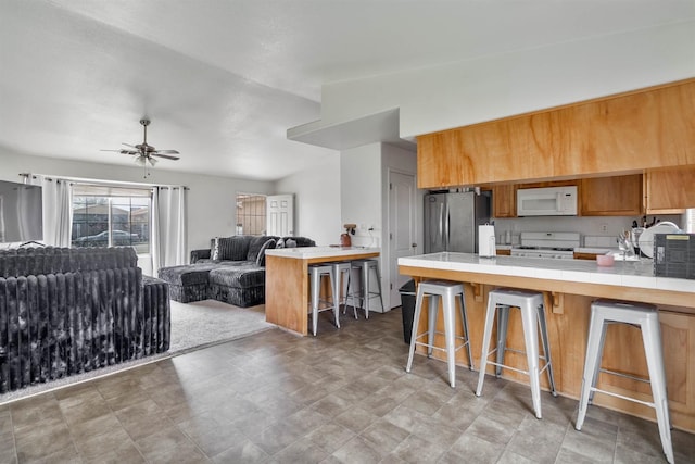 kitchen featuring white appliances, a peninsula, tile countertops, a kitchen bar, and open floor plan