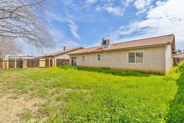 rear view of property with fence, stucco siding, cooling unit, and a tile roof