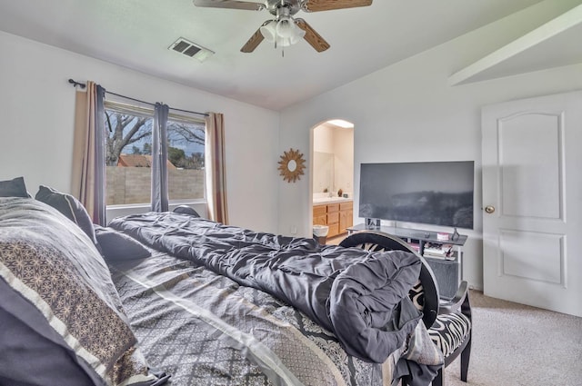 bedroom featuring vaulted ceiling, carpet flooring, arched walkways, ensuite bathroom, and ceiling fan