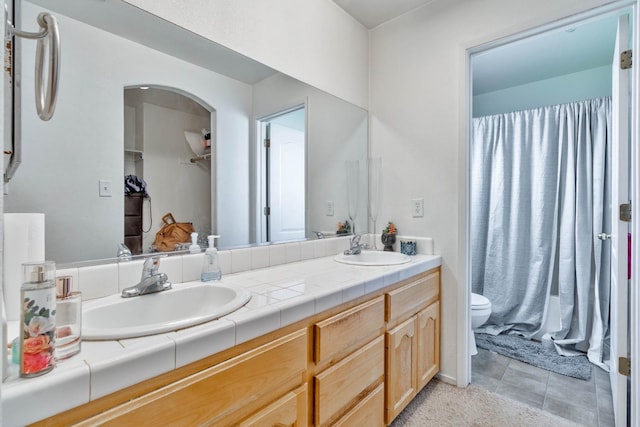 bathroom with double vanity, toilet, tile patterned floors, and a sink