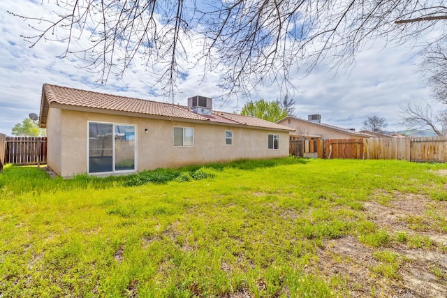 back of property with a tile roof, a yard, a fenced backyard, and stucco siding