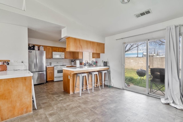 kitchen with white appliances, lofted ceiling, a peninsula, light countertops, and a breakfast bar area