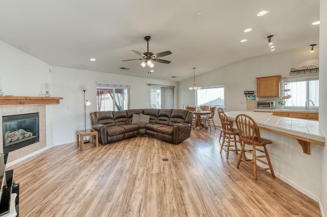 living room featuring a toaster, lofted ceiling, recessed lighting, a fireplace, and light wood-style floors