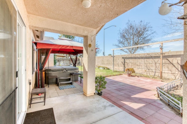 view of patio / terrace with a gazebo, a fenced backyard, and a hot tub