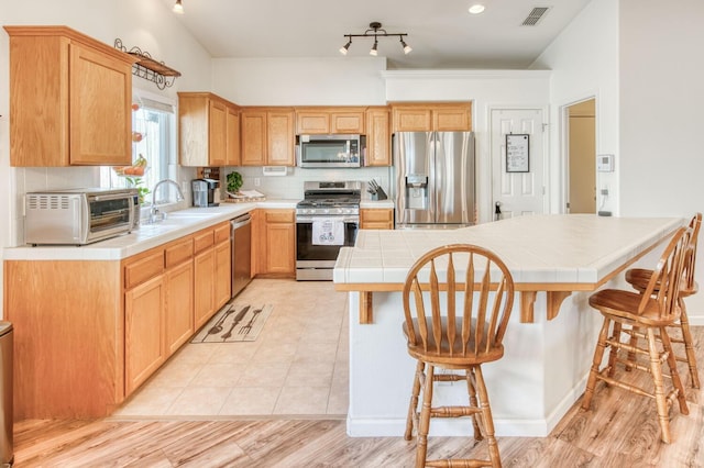 kitchen with visible vents, a sink, tile countertops, stainless steel appliances, and a toaster