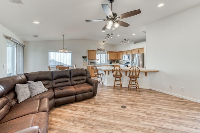 living room featuring visible vents, light wood finished floors, baseboards, lofted ceiling, and ceiling fan with notable chandelier