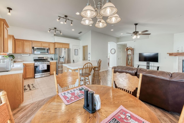 dining space with light tile patterned floors, arched walkways, and ceiling fan with notable chandelier