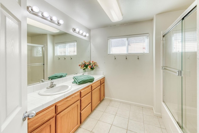 full bathroom with tile patterned floors, a healthy amount of sunlight, a shower with door, and a sink