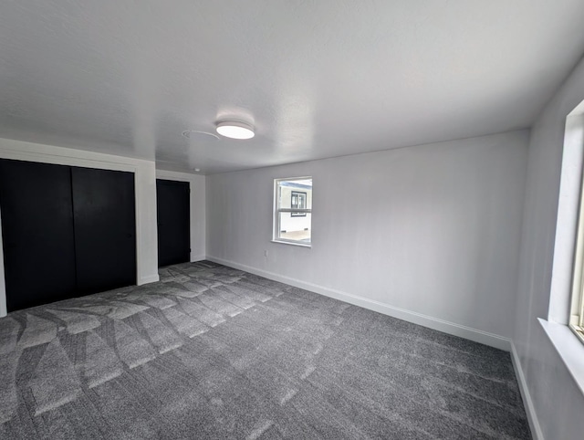 unfurnished bedroom featuring carpet, multiple closets, and baseboards