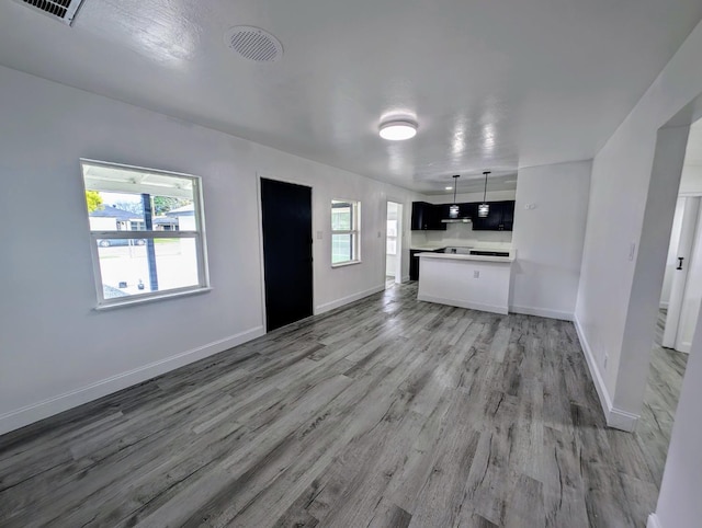 unfurnished living room featuring visible vents, baseboards, and light wood-style floors