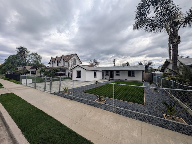 view of front of property with a front yard, a gate, stucco siding, concrete driveway, and a fenced front yard