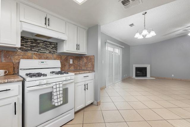 kitchen with visible vents, white gas range, under cabinet range hood, and a fireplace with raised hearth