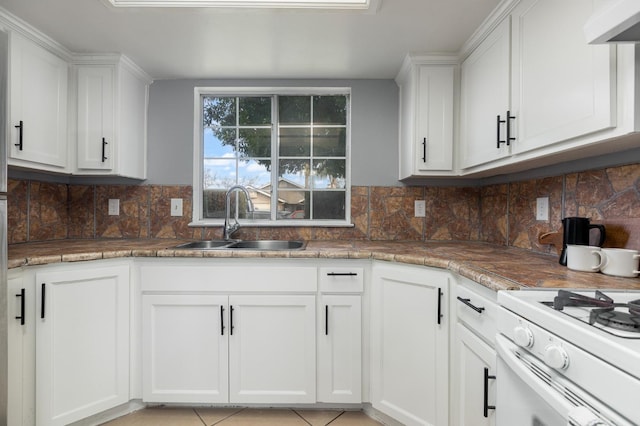 kitchen featuring a sink, gas range gas stove, ventilation hood, and white cabinetry