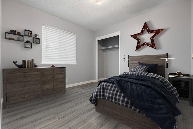 bedroom with baseboards, wood finished floors, a closet, and a textured ceiling