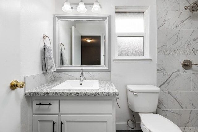 bathroom with vanity, toilet, tasteful backsplash, and a tile shower