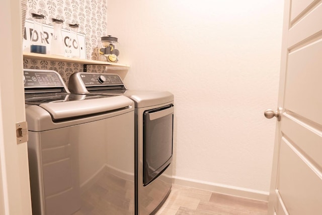clothes washing area with baseboards, washing machine and dryer, and laundry area