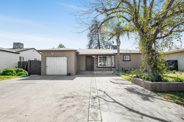 view of front of property featuring stucco siding, driveway, a gate, fence, and a garage