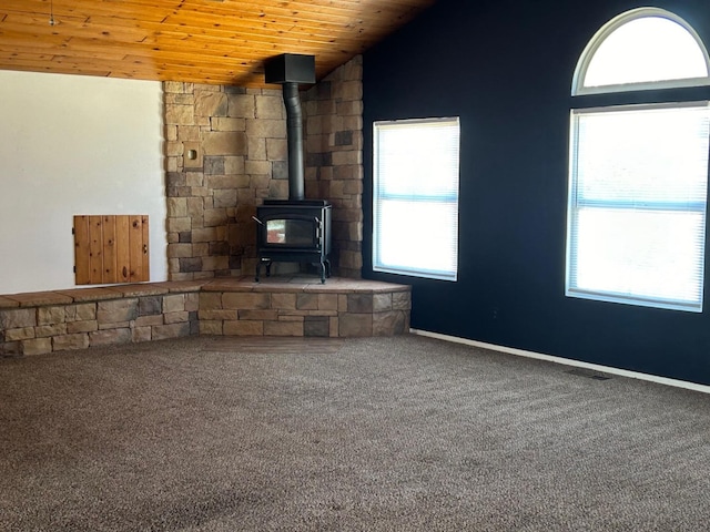 unfurnished living room featuring carpet flooring, wooden ceiling, a wood stove, and lofted ceiling