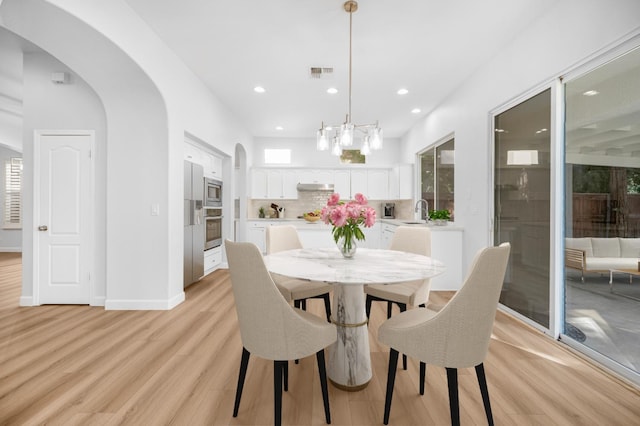 dining area featuring recessed lighting, visible vents, arched walkways, and light wood-style floors