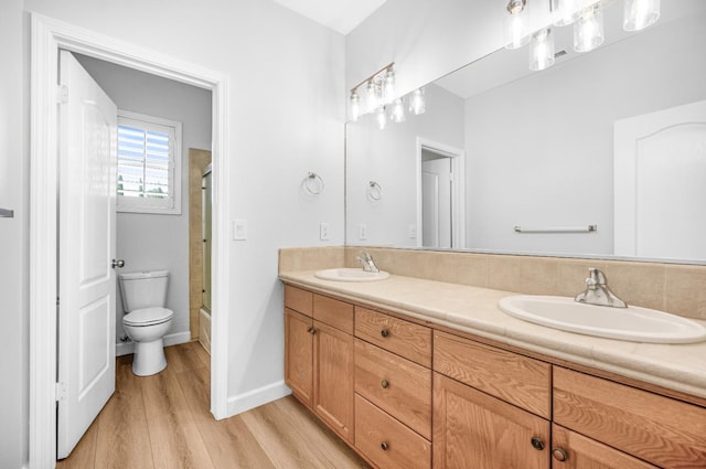 full bathroom with a sink, toilet, wood finished floors, and double vanity