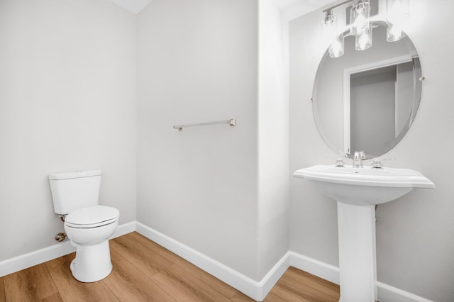 bathroom with toilet, baseboards, and wood finished floors