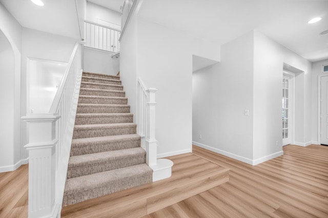 stairs with recessed lighting, baseboards, arched walkways, and wood finished floors