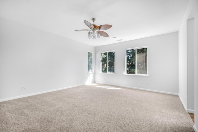 unfurnished room featuring a ceiling fan, visible vents, carpet, and baseboards