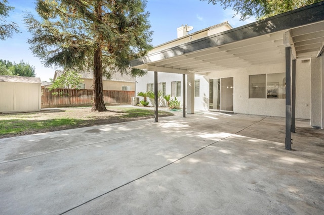 view of patio / terrace featuring a storage unit, an outdoor structure, and fence