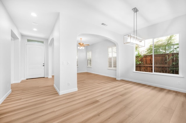 interior space with arched walkways, visible vents, and light wood finished floors