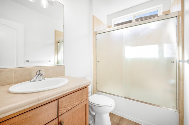 full bath with toilet, backsplash, wood finished floors, enclosed tub / shower combo, and vanity