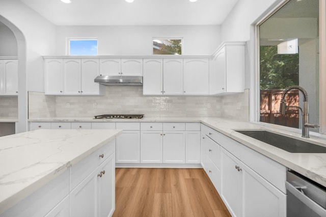 kitchen featuring under cabinet range hood, light wood-style flooring, white cabinets, stainless steel appliances, and a sink