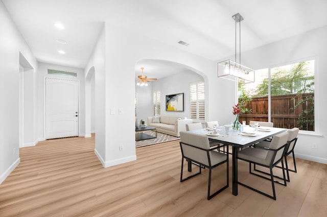 dining space with visible vents, arched walkways, and light wood finished floors