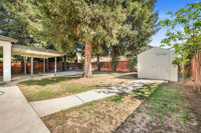 view of yard featuring an outbuilding, a storage unit, a fenced backyard, and a patio