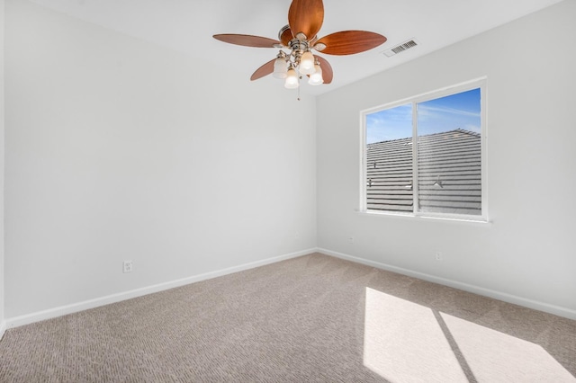 carpeted empty room with visible vents, baseboards, and a ceiling fan