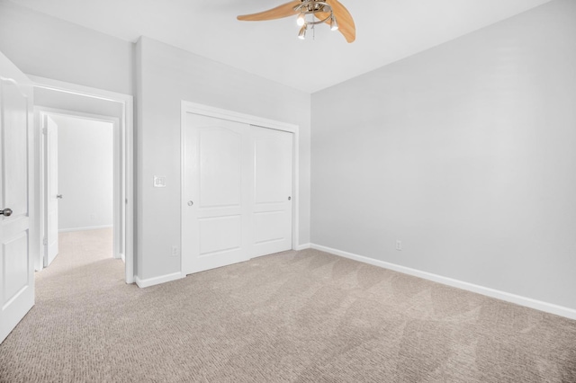 unfurnished bedroom with carpet flooring, a ceiling fan, baseboards, and a closet