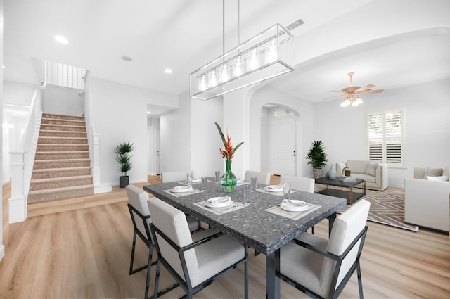 dining space with arched walkways, stairway, light wood-style flooring, and recessed lighting