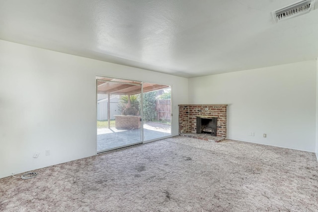 unfurnished living room featuring visible vents, a fireplace, a textured ceiling, and carpet