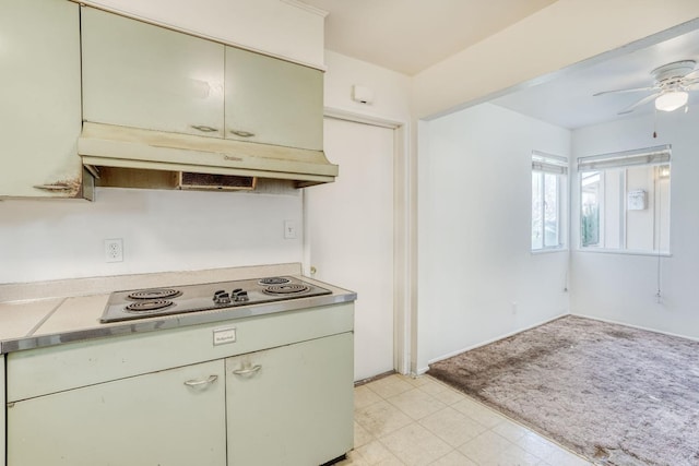 kitchen featuring ceiling fan, light countertops, under cabinet range hood, black electric stovetop, and light colored carpet