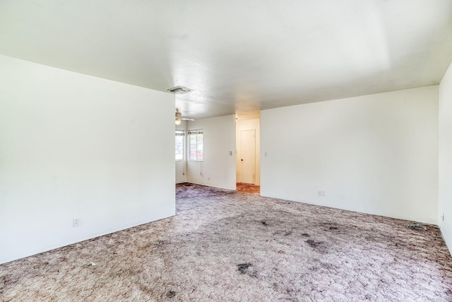 carpeted empty room featuring a ceiling fan and visible vents